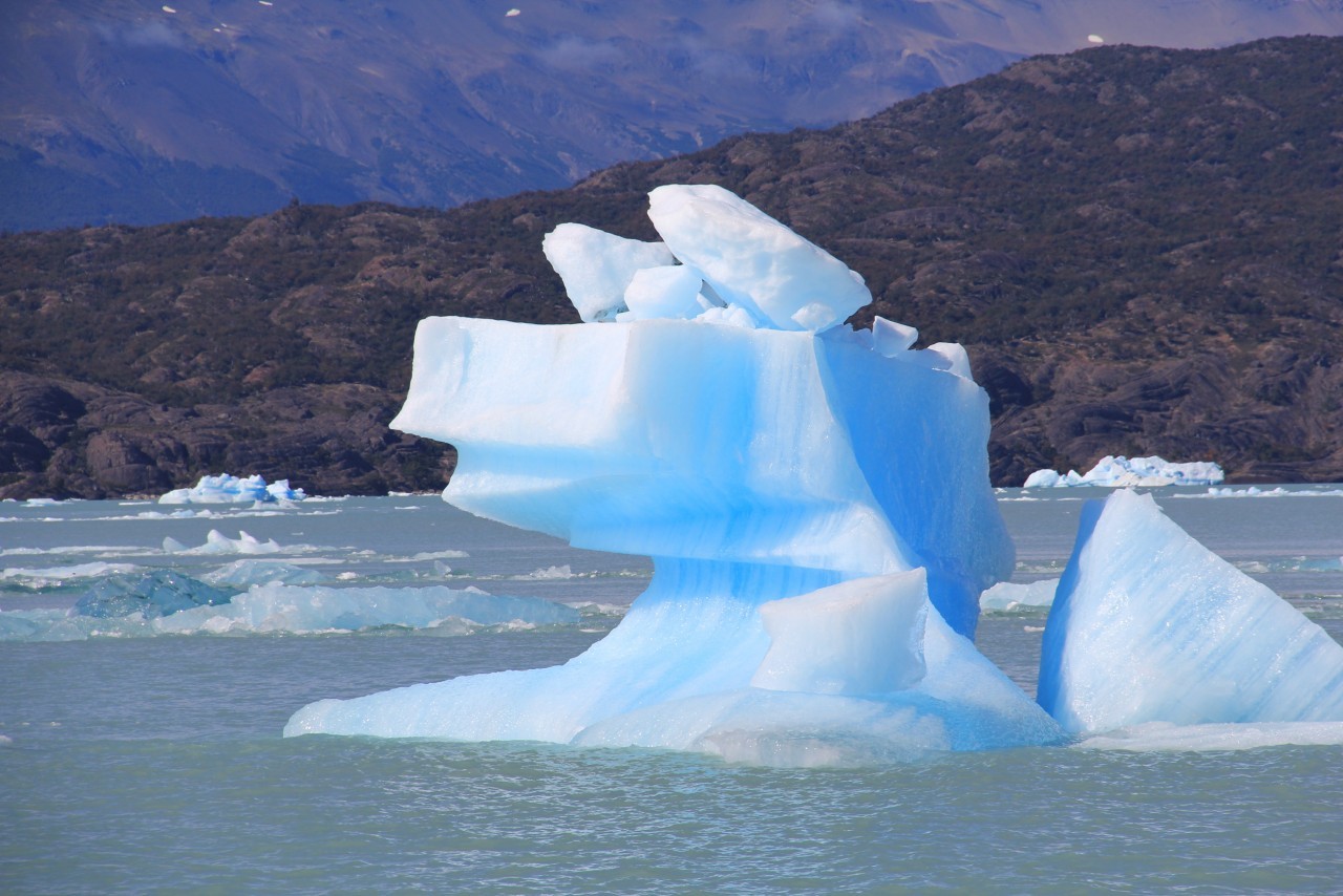 Iceberg bleu dérivant sur le lac Argentino près d'El Calafate, montagnes de Patagonie en arrière-plan
