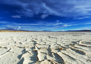 Croûte de sel craquelée en polygones sous un grand ciel bleu, Salinas Grandes