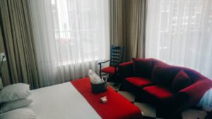 La suite junior en angle, avec vue sur la rue hollandaise. Le divan rouge, le lit king size, la lumière naturelle
