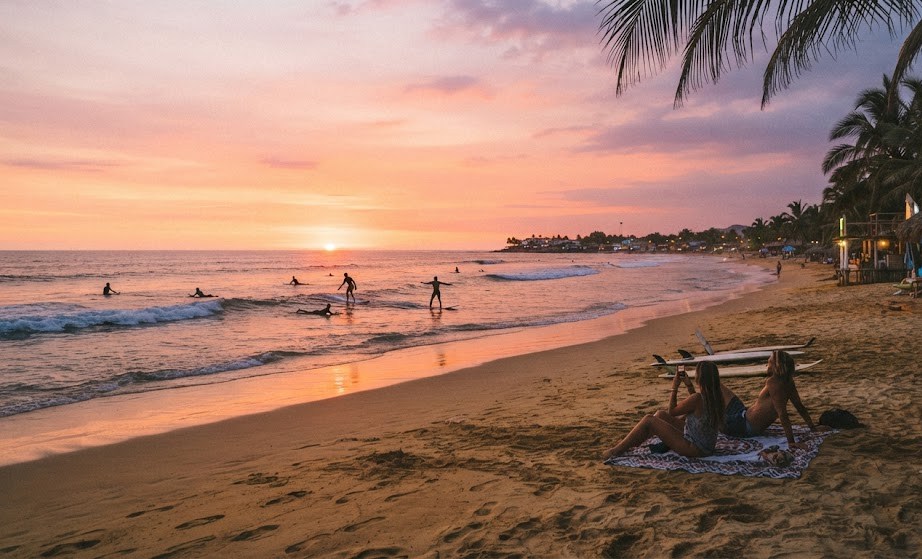  Plage de Máncora au Pérou, coucher de soleil sur le Pacifique, tons orangés et roses, silhouettes de surfeurs