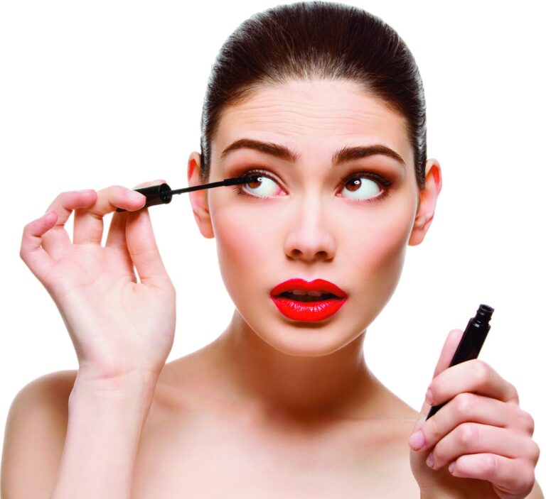 Jeune femme appliquant du mascara, les yeux levés